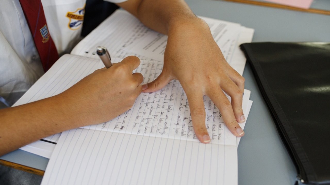 HSC_disability_provisions_image_16_9 A student writing in a notebook at a classroom desk.